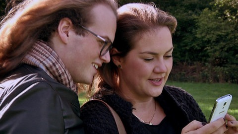 Julius und seine Schwester schauen auf ein Smartphone.