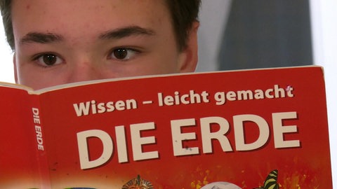 Jugendlicher liest in Themenheft "Die Erde"