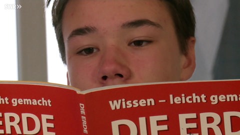 Mann sitzt an Tisch mit Papieren vor sich