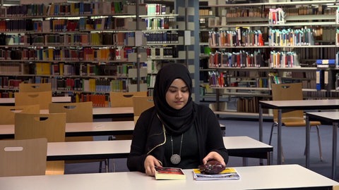 Junge Frau mit Kopfschleier in Bibliothek.