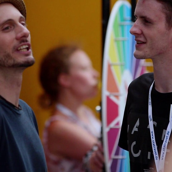 Es sind zwei junge Männer zu sehen, die sich gegenüber stehen.