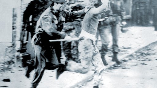 Ein Soldat schlägt auf einen Demonstranten ein