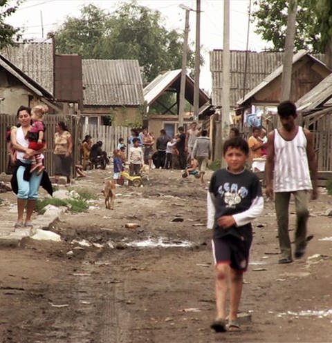 Ein Armutsviertel im Kosovo, es gibt keine richtige Straße, die Häuser sind heruntergekomme und die Menschen sehen arm aus.
