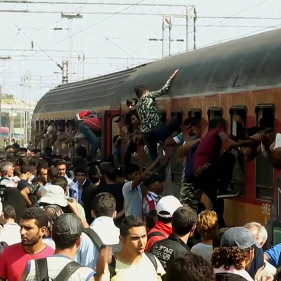 Flüchtlinge klettern von einem überfüllten Bahnsteig in einen ebenso vollen Zug
