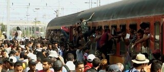 Flüchtlinge klettern von einem überfüllten Bahnsteig in einen ebenso vollen Zug
