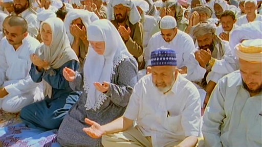 Menschen sitzen betend auf dem Boden.