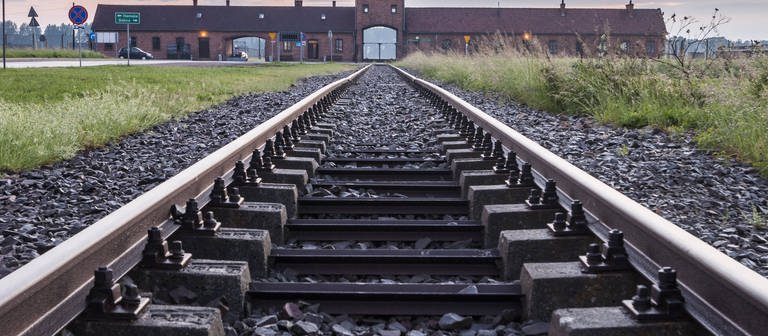 Ein Gleis führt Richtung Haupteingang des KZ Auschwitz