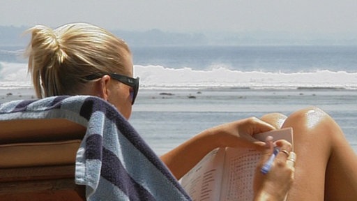 Blonde Touristin im Liegestuhl am Meer.