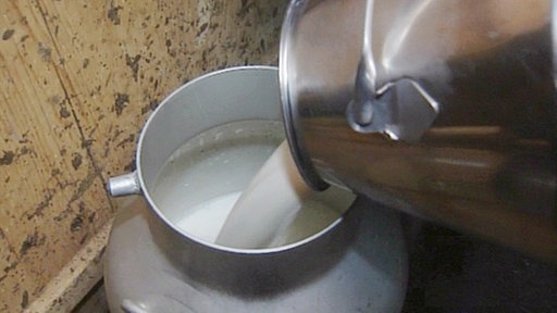 Milch wird von einer Kanne in eine andere umgegossen