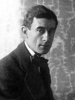 Schwarzweiß-Fotografie des Komponisten Maurice Ravel. Er trägt einen dunklen Anzug, ein weißes Hemd und eine dunkle Fliege und schaut ernst zur Kamera. (Foto: Public Domain)