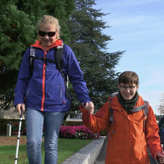 Rebekka und Florian laufen händehaltend mit Blindenstöcken die Straße entlang. (Foto: SWR - Screenshot aus der Sendung)