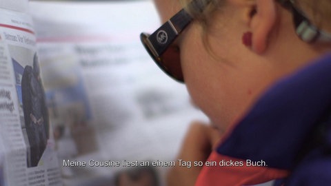 Rebekka liest mit Sonnenbrille eine Zeitschrift.