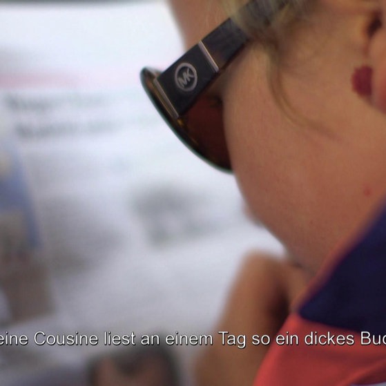 Rebekka liest mit Sonnenbrille eine Zeitschrift.