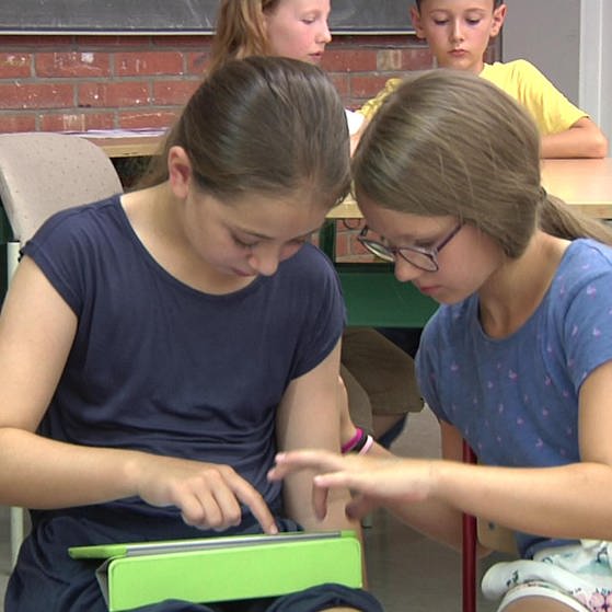 Zwei Mädchen sitzen in Klassenraum und nutzen gemeinsam ein Tablet (Foto: SWR, Ursi Zeilinger)