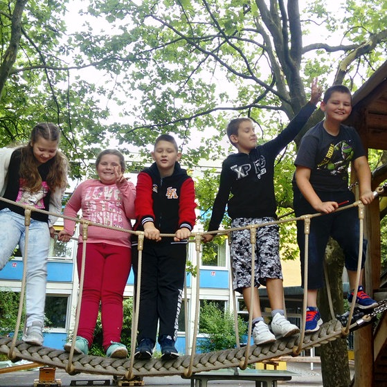 Fünf Kinder auf einer Spielplatz-Hängebrücke