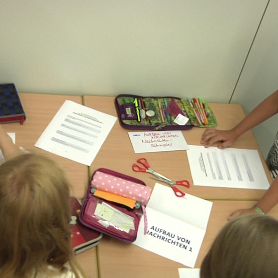 Kinder um einen Tisch mit Mäppchen und Blättern