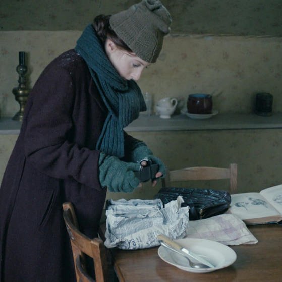 Spielszene: Edith Wellspacher steht warm angezogen am Küchentisch. (Foto: SWR/arte/Co. – Screenshot aus der Sendung)