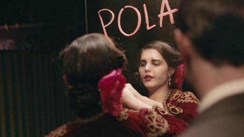 Filmszene: Michalina Olszanska schreibt mit Lippenstift POLA an einen Spiegel.