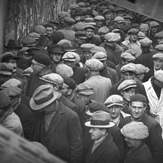 Historische Aufnahme: Dicht gedrängte Menge wartet vor einem Gebäude.