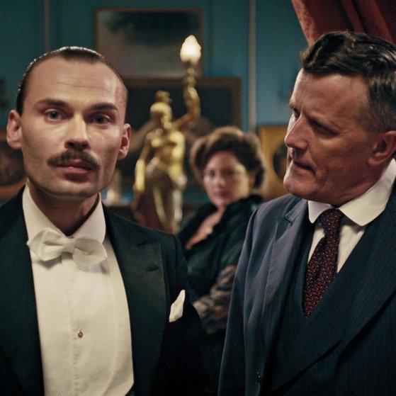 Spielszene: Marcel Jamet (links) im Gespräch mit dem Bankier.