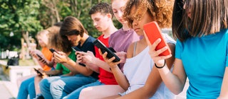 Junge Menschen sitzen in einer Reihe und schauen jeweils aufs Smartphone.