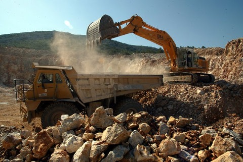 In einem Steinbruch wird ein Laster von einem Bagger beladen