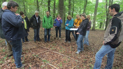 Gruppe Männer und Frauen steht einem Wald.