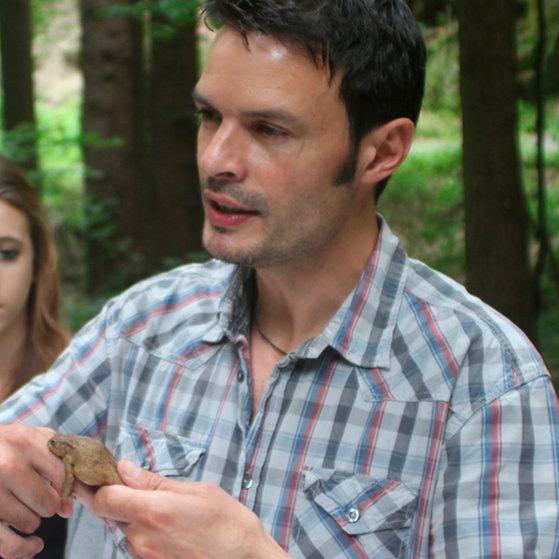 Oliver Euskirchen hält einen Froschlurch in den Händen.