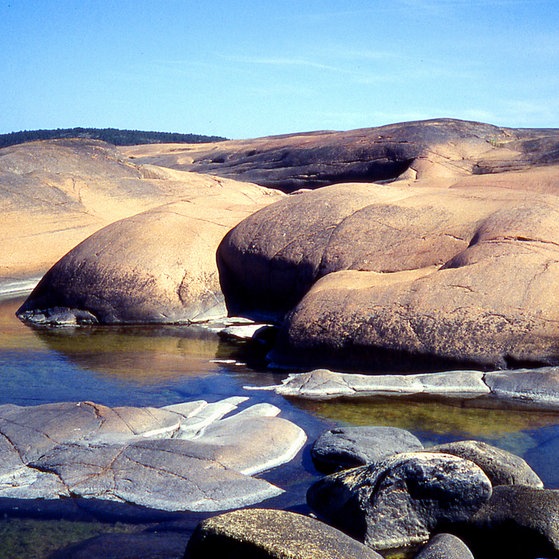 Küstenlandschaft mit großen, abgerundeten und glatten Felsen.