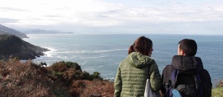 Zwei Menschen stehen an der Küste.