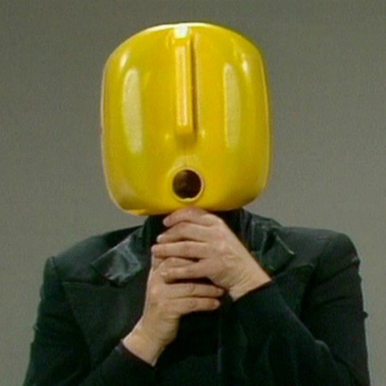 Ein gelber Kanisterkopf fasst sich ans Kinn.