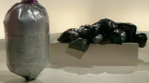 Der silberne Sack steht vor dem schwarzen Sack auf dem Podest.