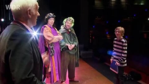 Terry Deary mit zwei Schauspielern und Huck McKenna auf einer Theaterbühne (Foto: footstep production/WDR)