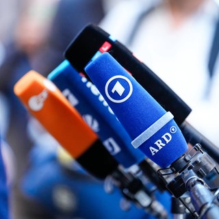 Mehrere Mikrofone von verschiedenen Medien auf einem Tisch. Wie werden Nachrichten gemacht? Warum sind Nachrichten wichtig?