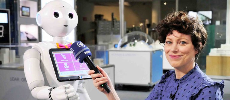 neuneinhalb-Reporterin Malin hält dem humanoiden Roboter 'Pepper' ihr Mikro hin. (Foto: WDR, tvision)
