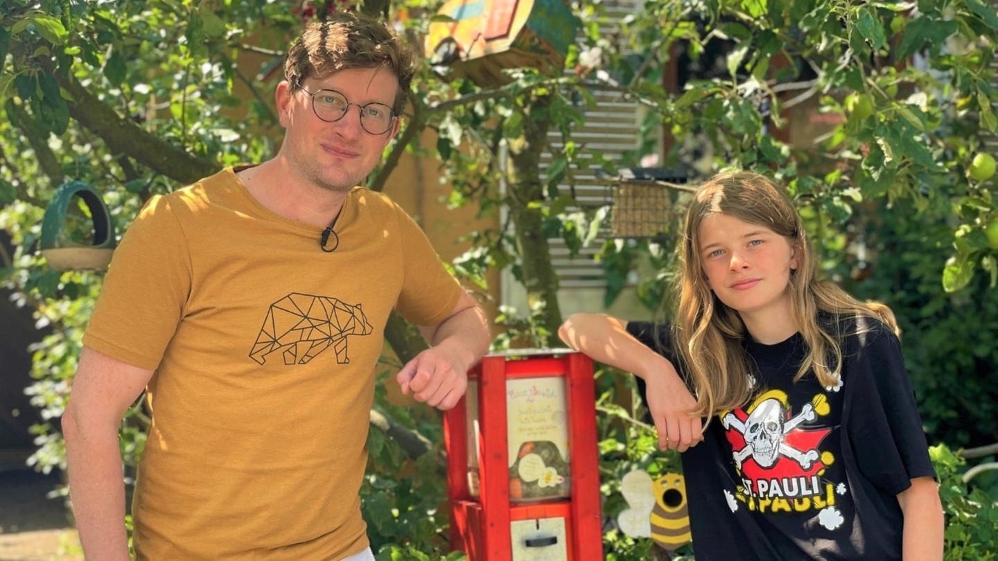 neuneinhalb-Reporter Robert und Jonte (14) stehen vor seinem umgebauten Kaugummiautomaten. Daraus kann man sich nun Samen für Blühwiesen ziehen. (Foto: WDR, tvision)