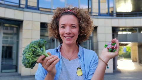 neuneinhalb-Reporterin Gesa hält einen Brokkoli und eine Handvoll Bonbons ins Bild. (Foto: WDR, tvision)