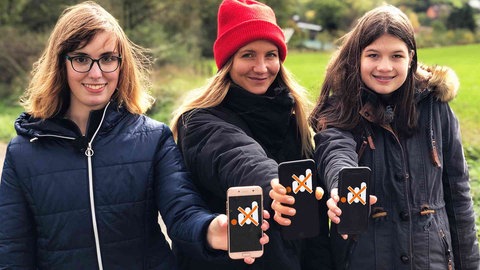 Leonie, neuneinhalb-Reporterin Jana und Mara halten Smartphones in die Kamera