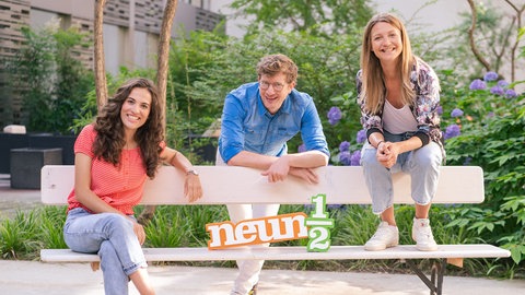 neuneinhalb-Reporter:innen Mona, Robert und Jana auf einer Bank mit dem Schriftzug 