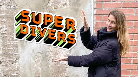 Reporterin Jana vor einer Mauer, sie zeigt auf die Aufschrift 