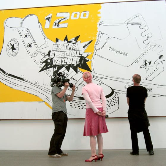 Enie van der Meiklokjes und Prof. Wolfgang Flatz vor Andy Warhols Bild " Converse Extra Special Value". (Foto: SWR/megaherz/Robert Mayer)