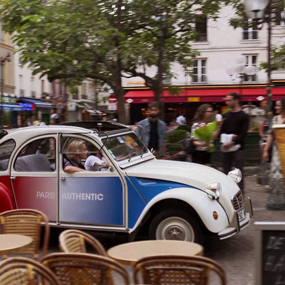 2CV in Frankreichfarben fährt durch Paris.