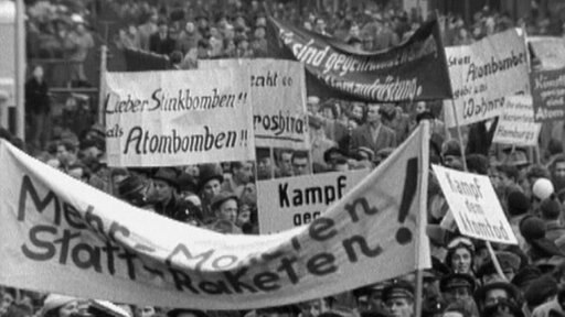 Demonstranten mit Transparenten: „Lieber Stinkbomben als Atombomben, „Kampf dem Atomtod“, „Mehr Moneten statt Raketen“
