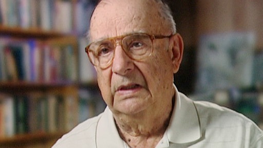 Nahaufnahme CIA-Mitarbeiter Dino Brugioni im Interview vor Bücherregal