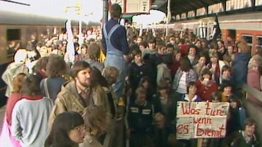 Demonstranten am Bahnhof, Treppenabgang, Transparent “Was tun, wenn es brennt”