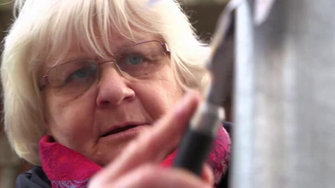 Irmela Mensah-Schramm kratzt Kleber ab. (Foto: SWR – Screenshot aus dem Film)