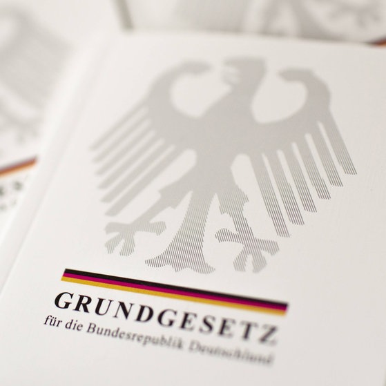 Mehrere Ausgaben des Grundgesetzes liegen übereinander.