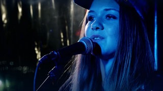 Ciera spielt ihre eigenen Songs auf Gitarre und singt dazu.