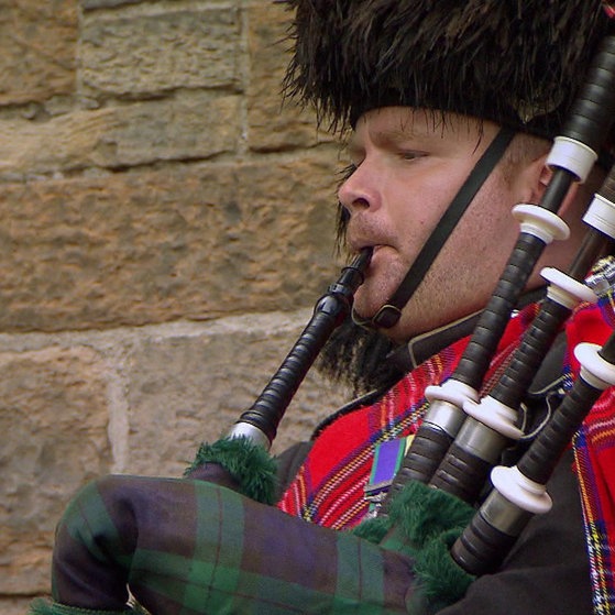 Mann im Schottenoutfit spielt Dudelsack.