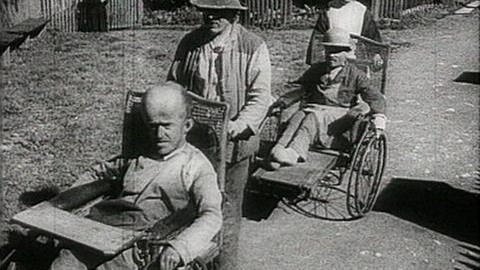 Schwarz-weiß Bild von Menschen im Rollstuhl.